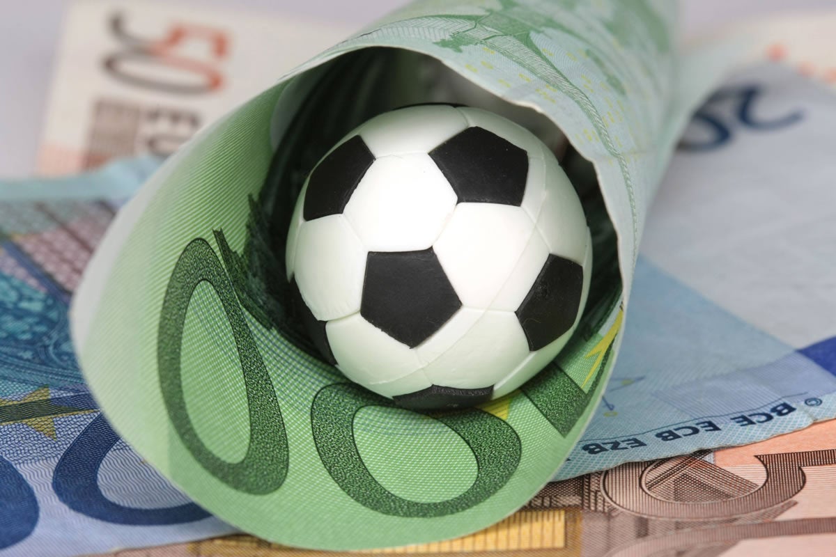 A football lies in a rolled-up 100 euro note.