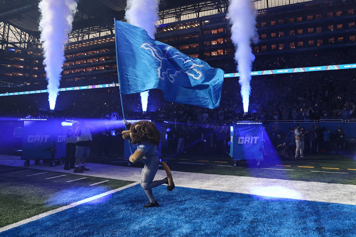 Das Maskottchen der Detroit Lions, Roary, läuft auf das Spielfeld und trägt die Flagge mit dem Teamlogo vor dem Beginn eines NFL, American Football Herren, USA Footballspiels zwischen den Minnesota Vikings und den Detroit Lions am 7. Januar 2024 im Ford Field in Detroit, Michigan. 