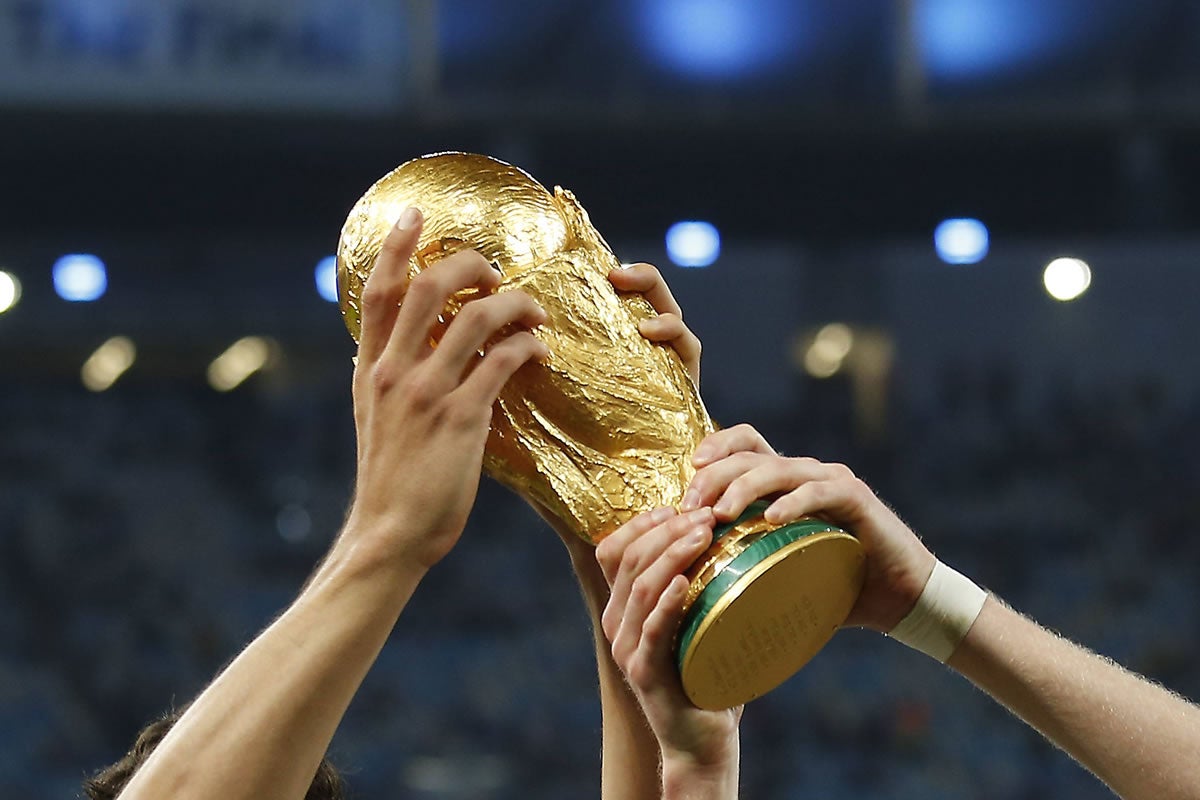 Vier Häne halten den WM Pokal in die Höhe.