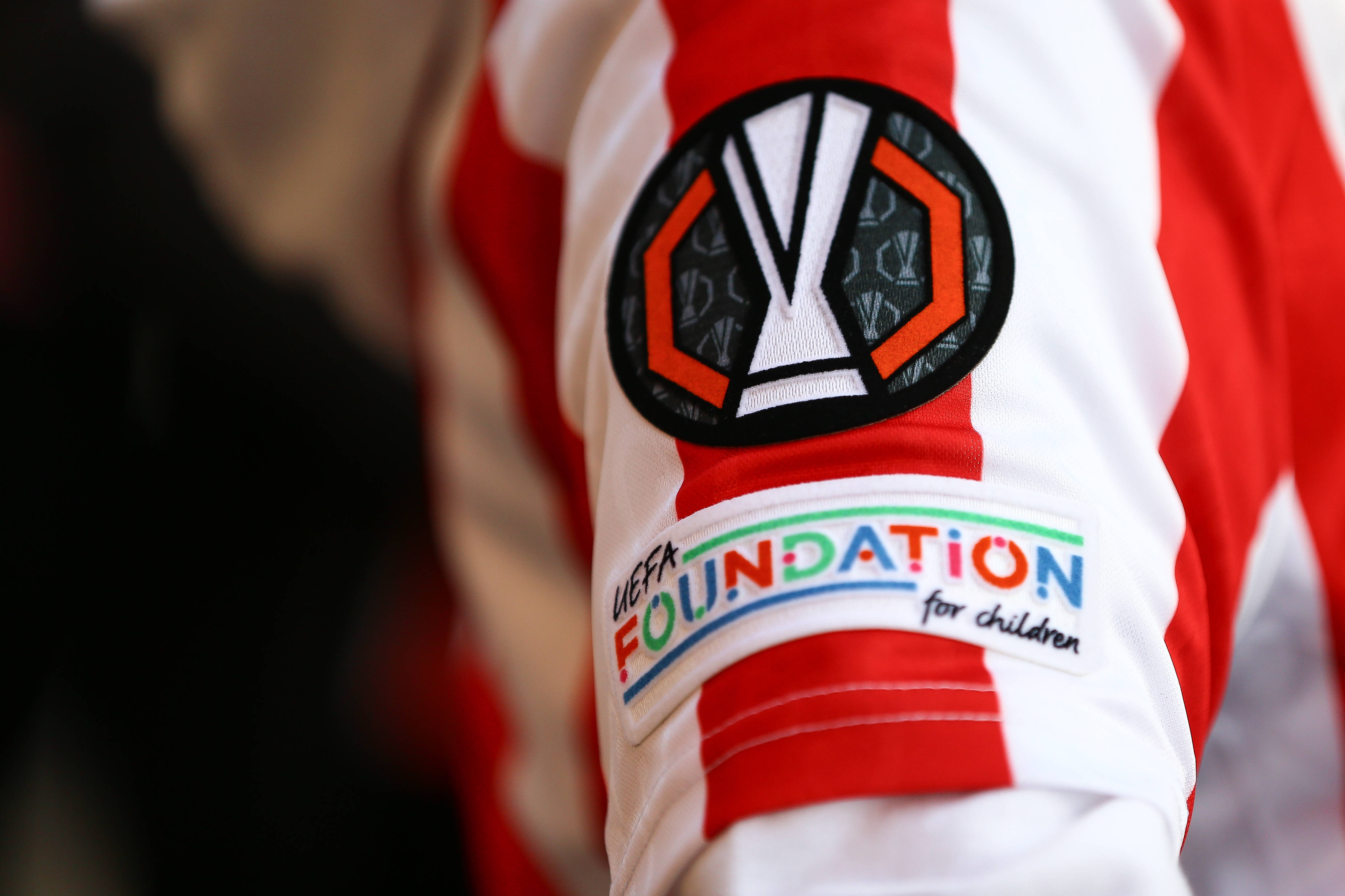 Foto vom Ärmel eines rot-weiß gestreiften Fußballtrikots mit Europa-League-Logo sowie "UEFA Foundation for Children"-Aufnäher