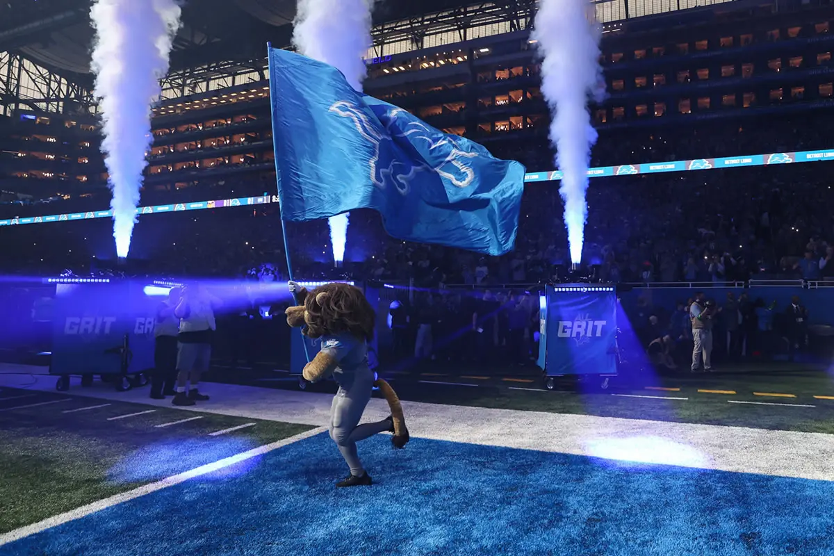 Das Maskottchen der Detroit Lions, Roary, läuft auf das Spielfeld und trägt die Flagge mit dem Teamlogo vor dem Beginn eines NFL, American Football Herren, USA Footballspiels zwischen den Minnesota Vikings und den Detroit Lions am 7. Januar 2024 im Ford Field in Detroit, Michigan.