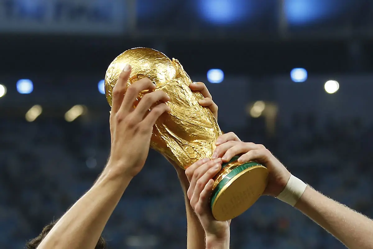 Vier Häne halten den WM Pokal in die Höhe.