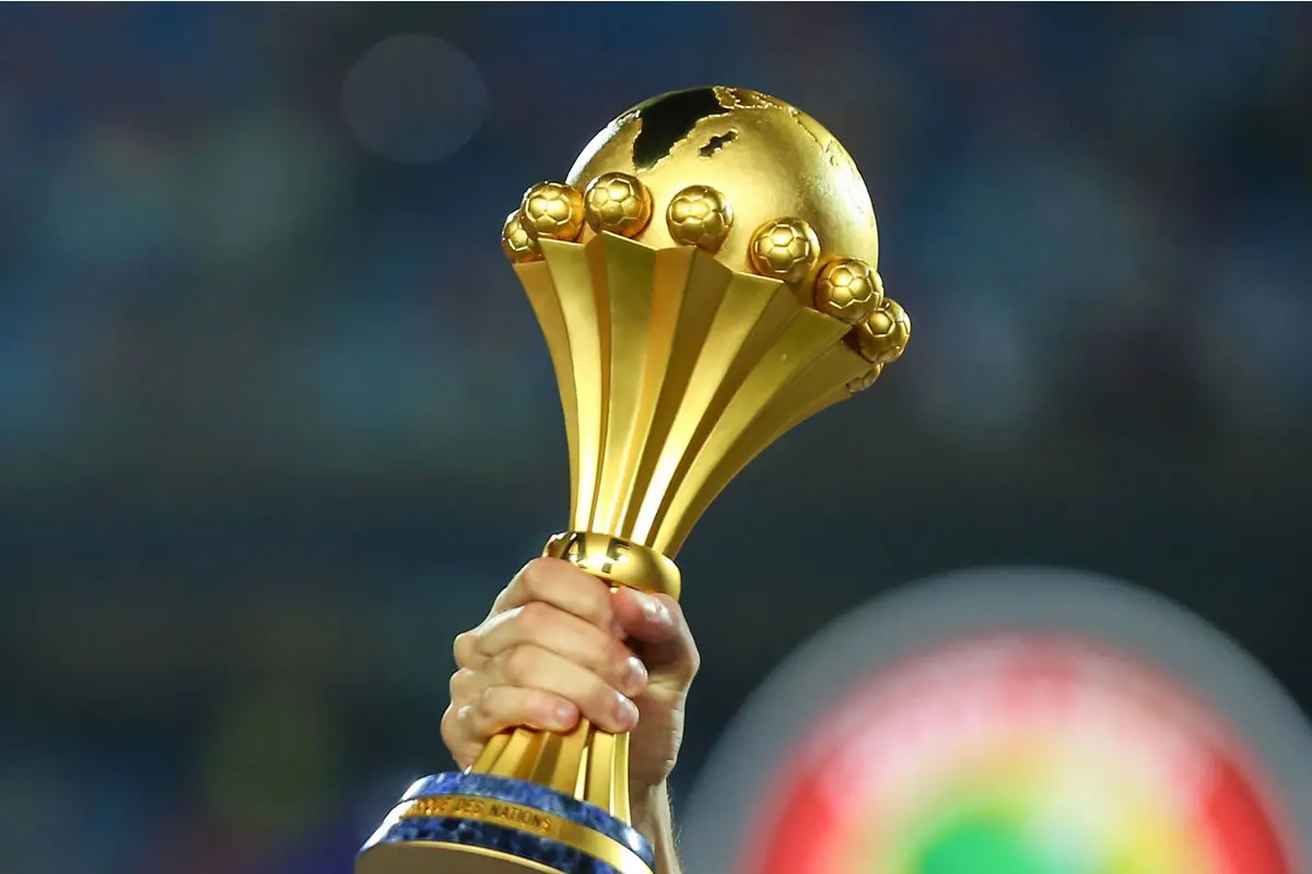 Eine Hand hält den Siegerpokal des Afrika Cups in die Höhe.